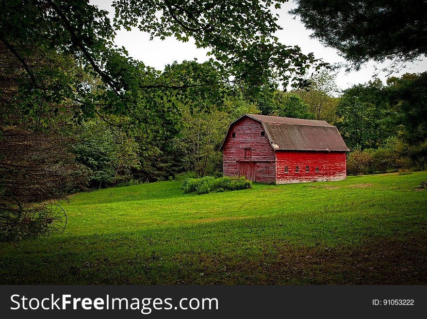 Barn in the Middle of Lawn Surrounded With Trees during Daytime