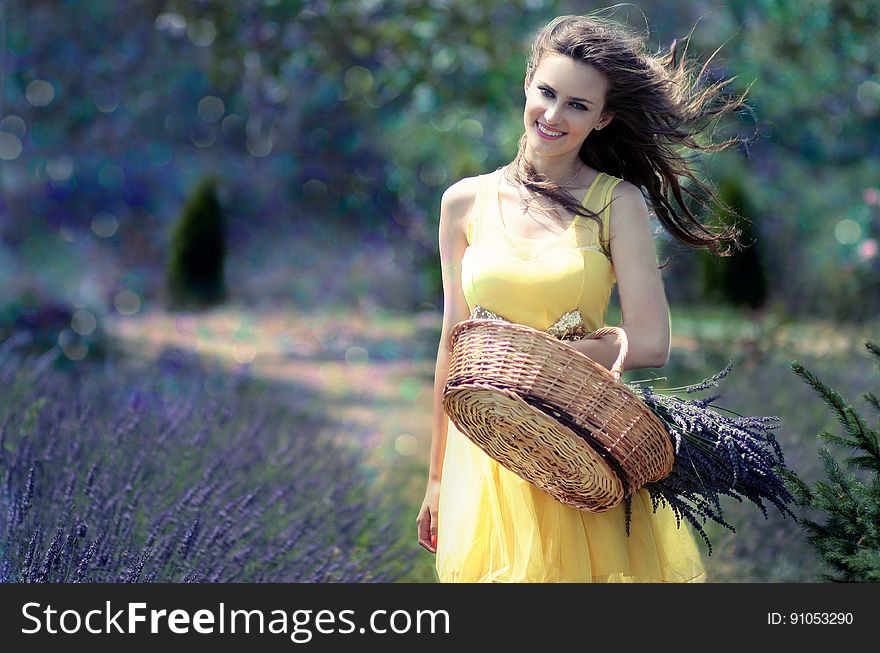 Woman in Yellow Maxi Dress Holding Brown Woven Picnic Basket Walking During Daytime