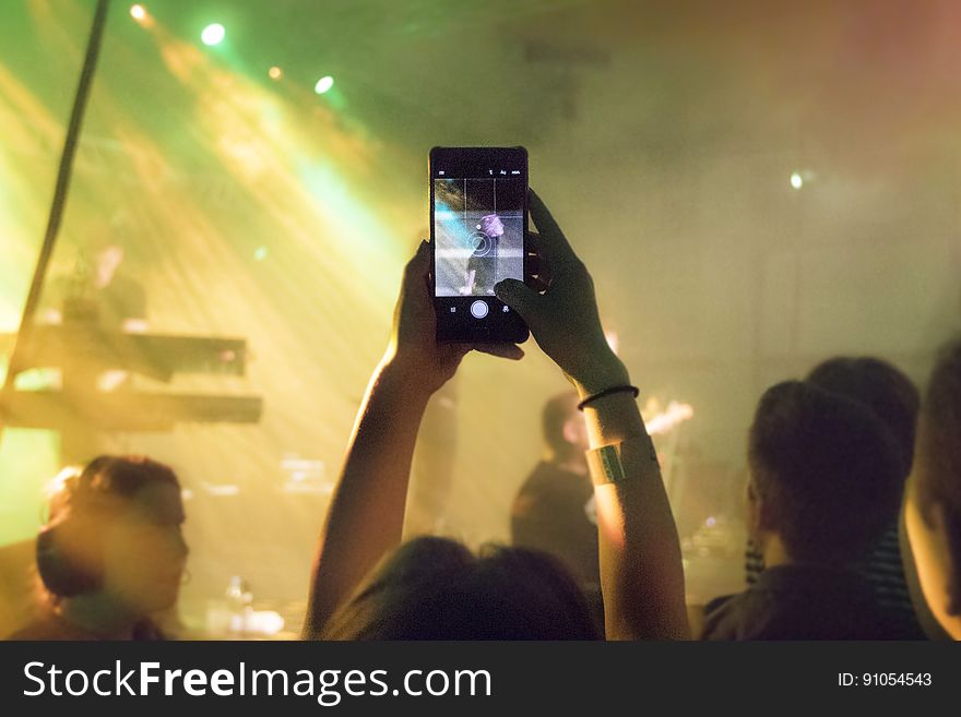 A man taking a photo of the musicians at a concert. A man taking a photo of the musicians at a concert.