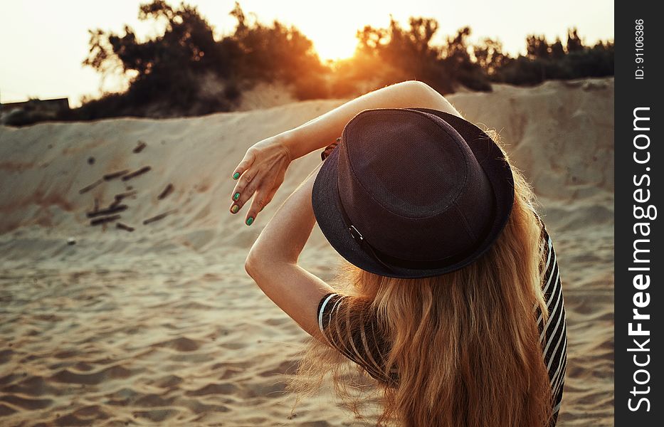 A young woman with a hat on a sandy beach looking at the morning sun. A young woman with a hat on a sandy beach looking at the morning sun.