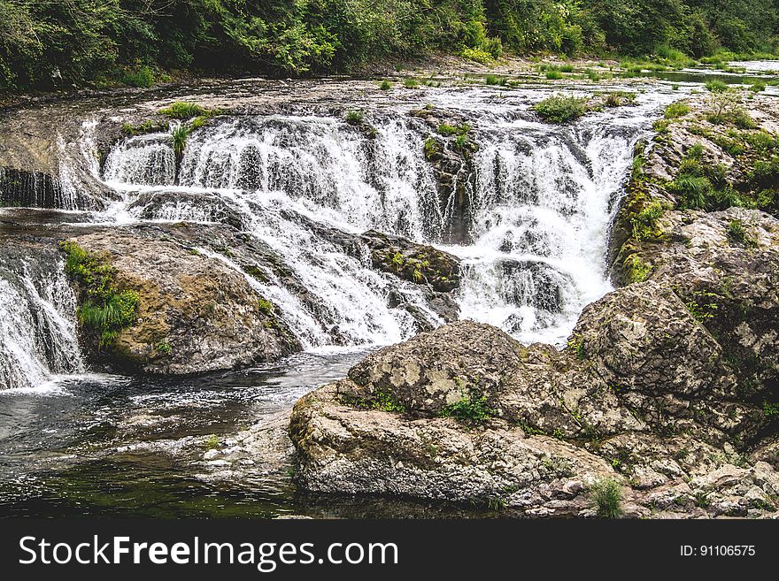 Water in stream over rocks creating rapids on sunny day. Water in stream over rocks creating rapids on sunny day.