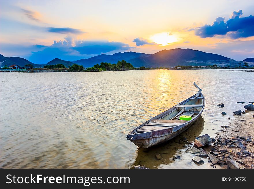 Wooden boat on shoreline of lake in mountains at dawn. Wooden boat on shoreline of lake in mountains at dawn.