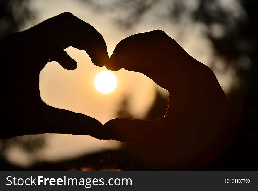 Silhouette Of Person Hand Doing Heart Shape During Sunset