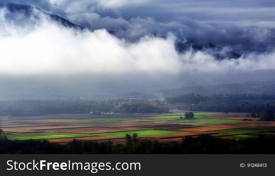 Landscape Photography of Green and Brown Rice Field Surrounded With White and Blue Clouds Near Black Mountains