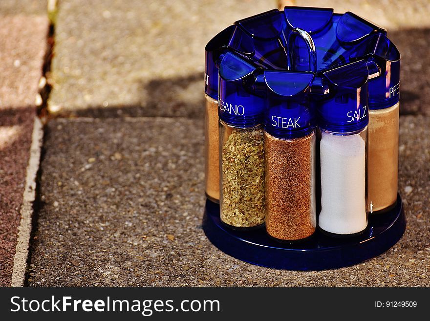 Clear tubes of seasonings with blue caps in rack outside on paving stones. Clear tubes of seasonings with blue caps in rack outside on paving stones.