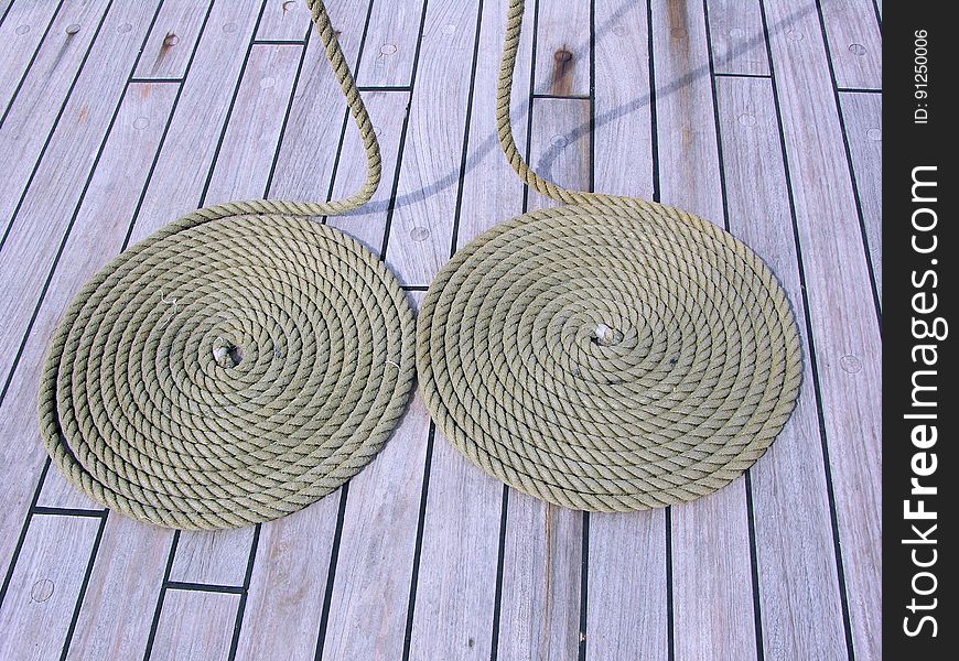 A pair of coils of rope on wooden floor.