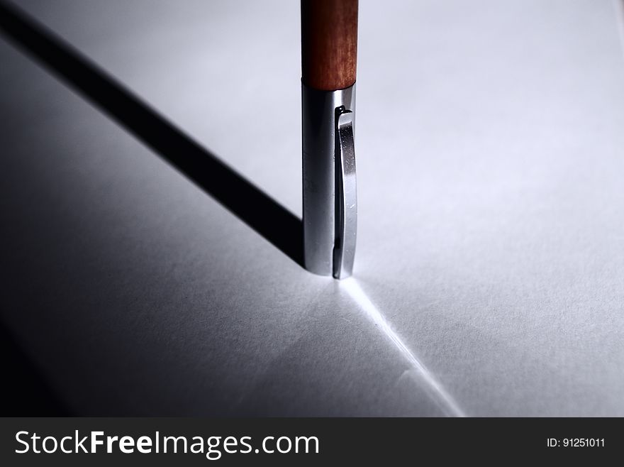 A close up of a pen and its shadow on a table.