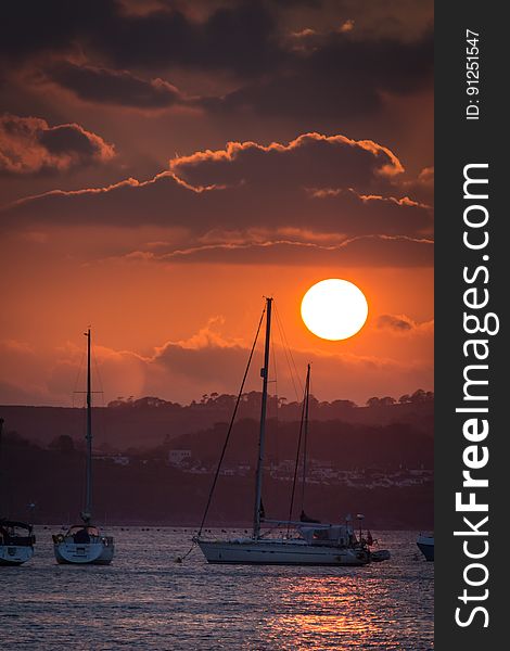 Sunset in orange skies over sailboats in marina. Sunset in orange skies over sailboats in marina.