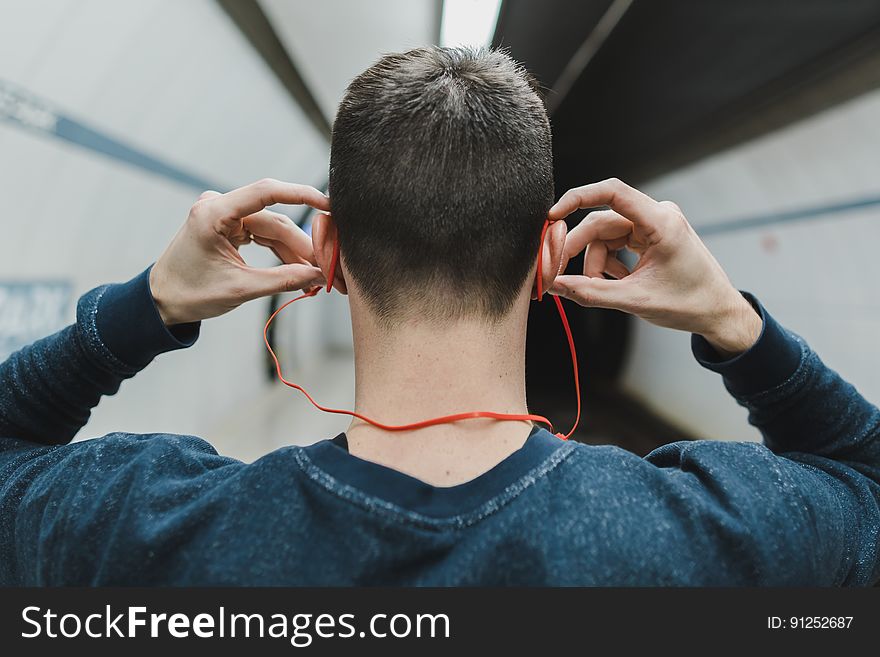 Man in subway putting earphones in ears