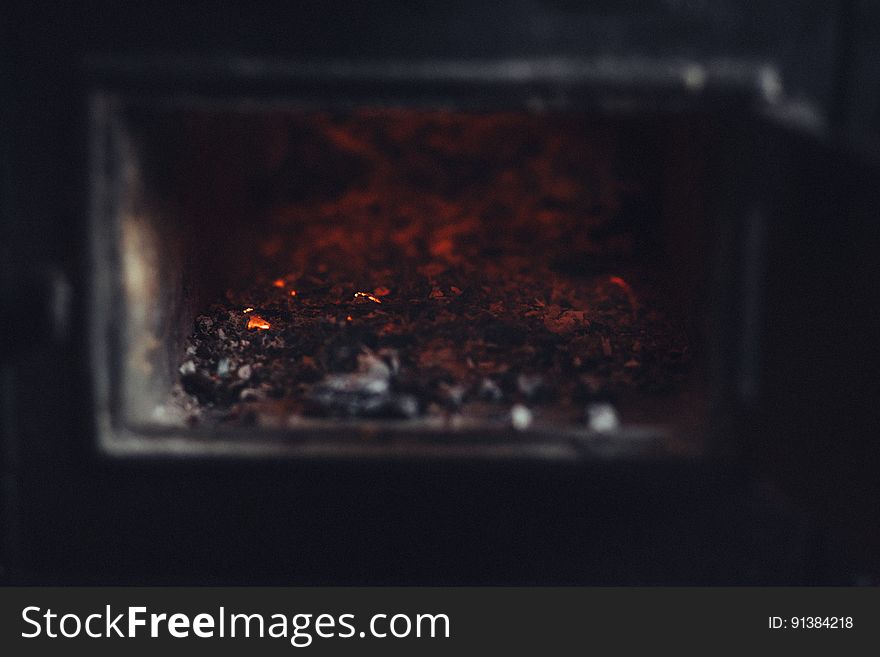 Glow of burning coal embers in fireplace.