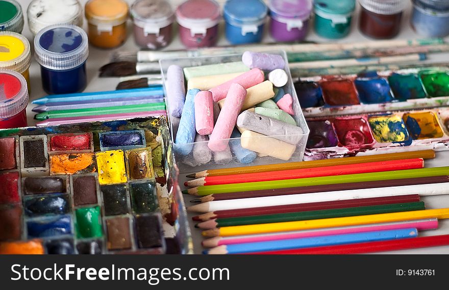 Items for drawing and art: crayons, watercolor paints, brushes, colored pencils.