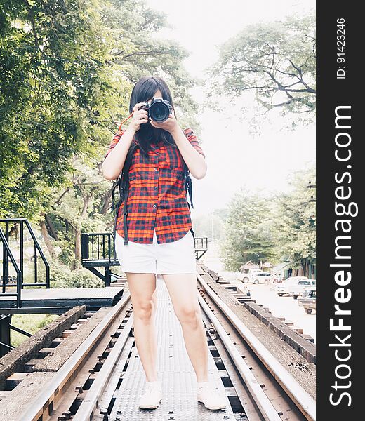Happy asian woman on vacation photographing with a dslr camera on railway in forest