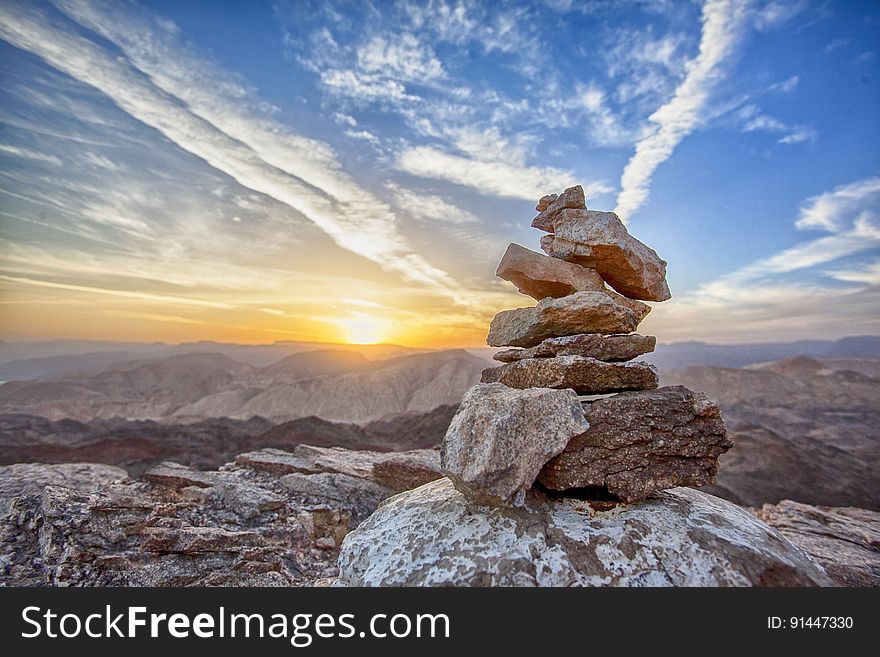 Pile of rocks on ledge on cliff of mountain landscape with sunrise in blue skies. Pile of rocks on ledge on cliff of mountain landscape with sunrise in blue skies.