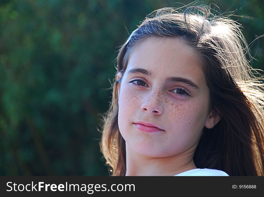 Brunette tween schoolgirl gazing at the camera on a spring afternoon.