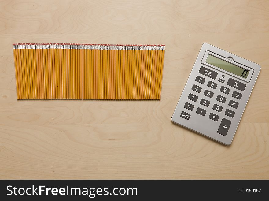 Overhead shot of calculator and Pencils on wood desk