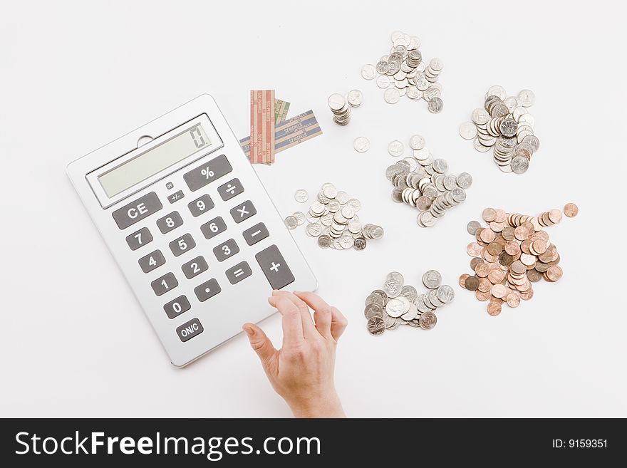 Single hand using calculator to add piles of coins. Single hand using calculator to add piles of coins