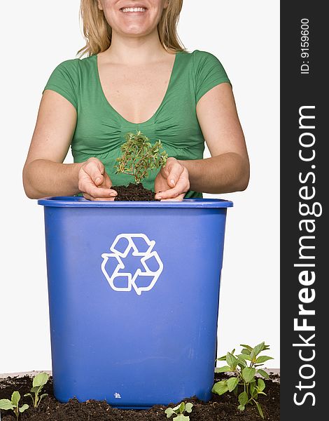 Woman holding small tree over recycling bin. Woman holding small tree over recycling bin