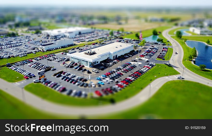 Modern manufacturing factories with extensive car parking and parked cars. The buildings are on a green field site with access roads, lake and selective focus on the nearest building. Modern manufacturing factories with extensive car parking and parked cars. The buildings are on a green field site with access roads, lake and selective focus on the nearest building.