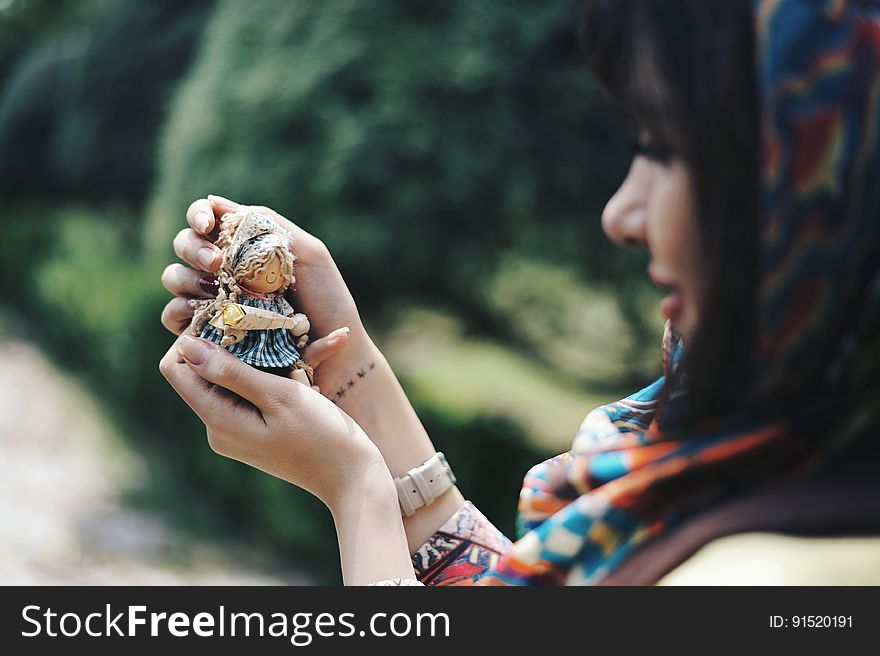 Woman holding a tiny doll and looking at it