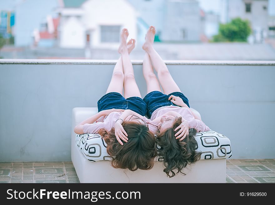 Twin girls laying outdoors on twin beds in urban setting. Twin girls laying outdoors on twin beds in urban setting.