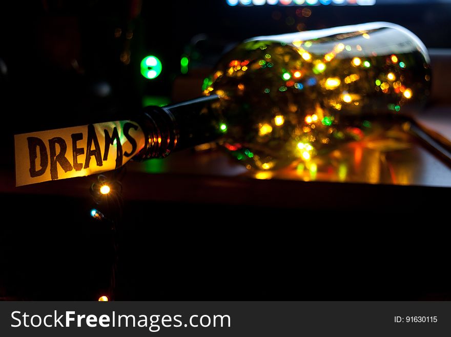 A bottle with Christmas lights inside and a note saying "Dreams" on the top. A bottle with Christmas lights inside and a note saying "Dreams" on the top.
