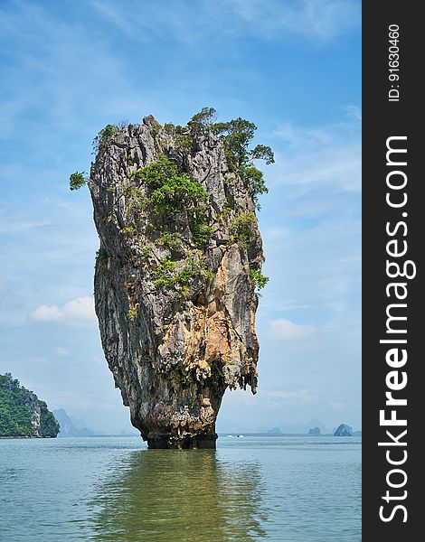 Scenic view of tropical limestone karst rock formation in sea with blue sky and cloudscape background. Scenic view of tropical limestone karst rock formation in sea with blue sky and cloudscape background.