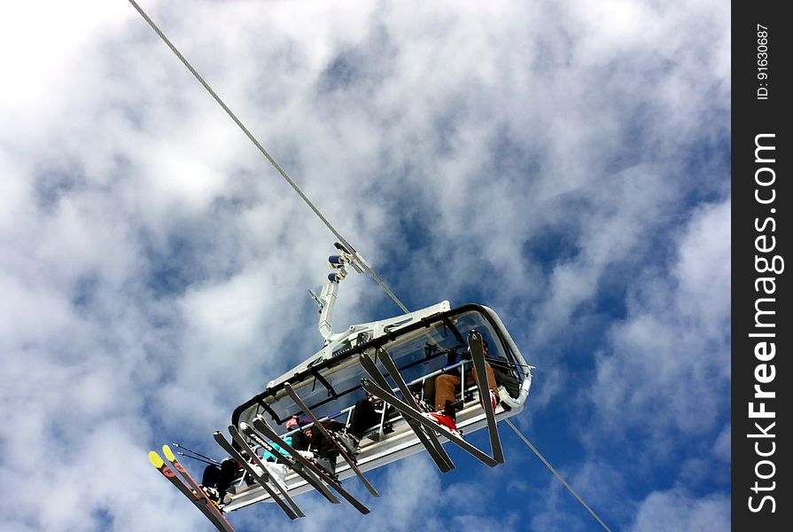 A chairlift with skiers from a low angle.