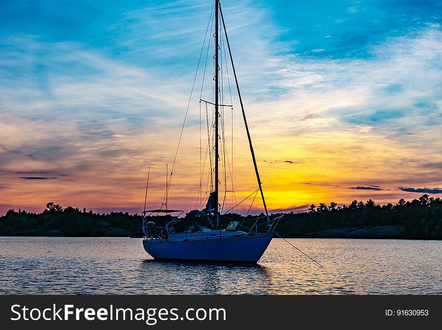 A sailboat in the sea at sunset. A sailboat in the sea at sunset.
