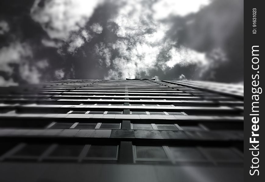 A low-angle view of a high-rise building in black and white. A low-angle view of a high-rise building in black and white.