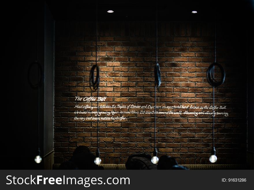 An interior brick wall and hanging lights in the foreground.