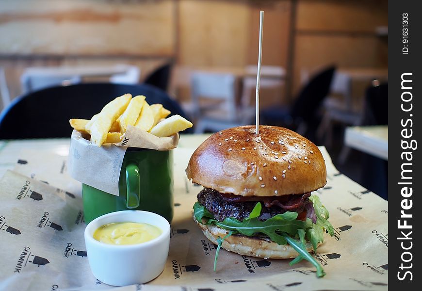 A burger with French fries and a dip on a table.