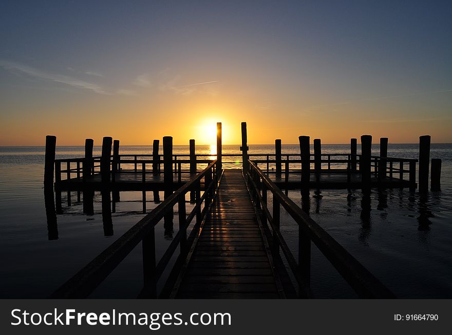 A silhouetted wooden pontoon at sunset.