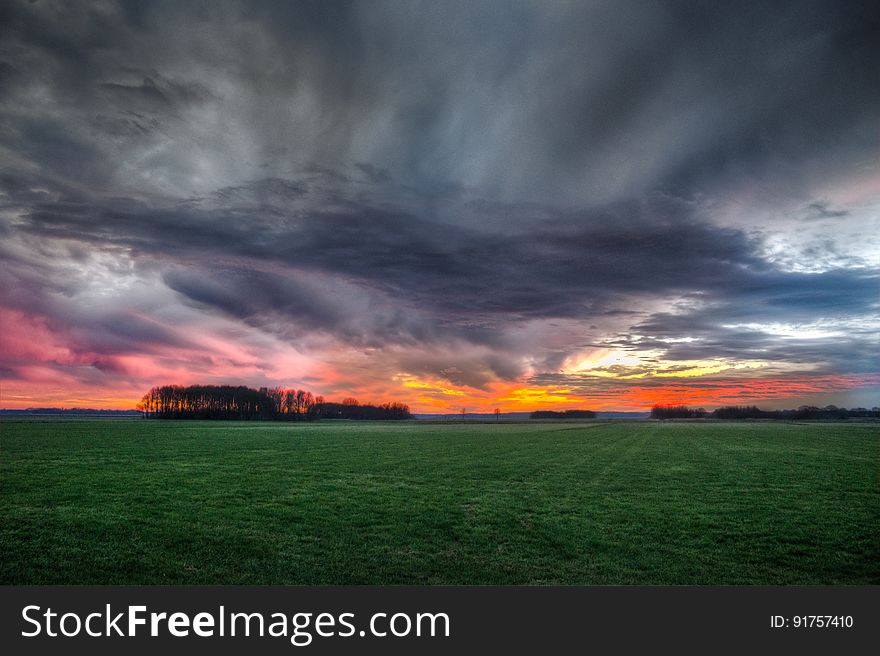 Storm Clouds over Field During Sunset