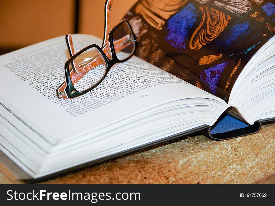 A close up of an open book with eyeglasses on it.