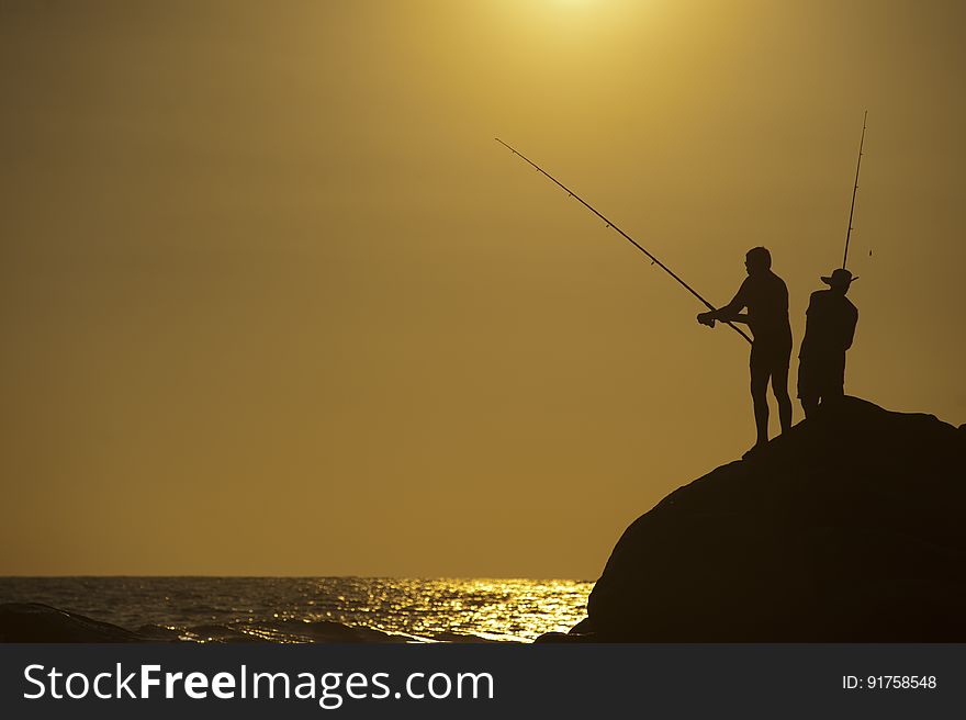 Fishers on a rock beside the sea