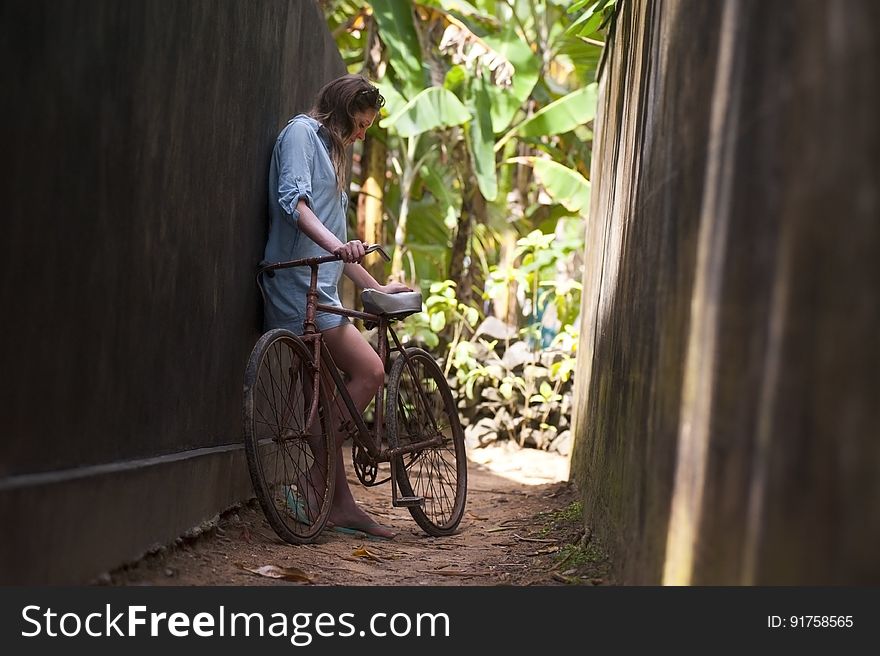 A girl with her bicycle on a narrow alley. A girl with her bicycle on a narrow alley.