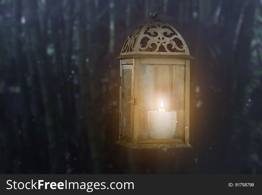 A lantern with a candle burning inside in the night. A lantern with a candle burning inside in the night.