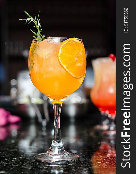 A cocktail with orange juice and rosemary. A cocktail with orange juice and rosemary.