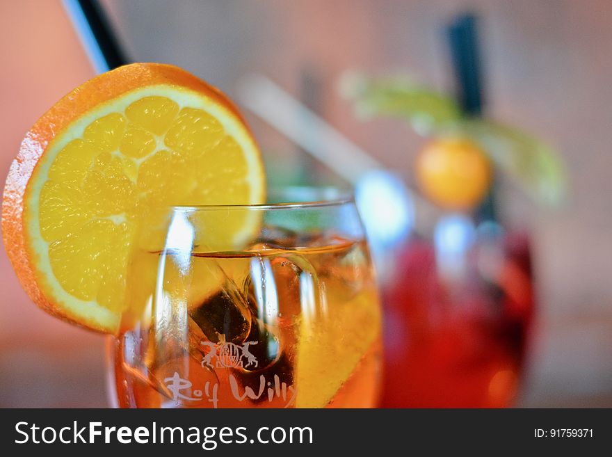 A cocktail in a glass with a slice of orange on the side. A cocktail in a glass with a slice of orange on the side.