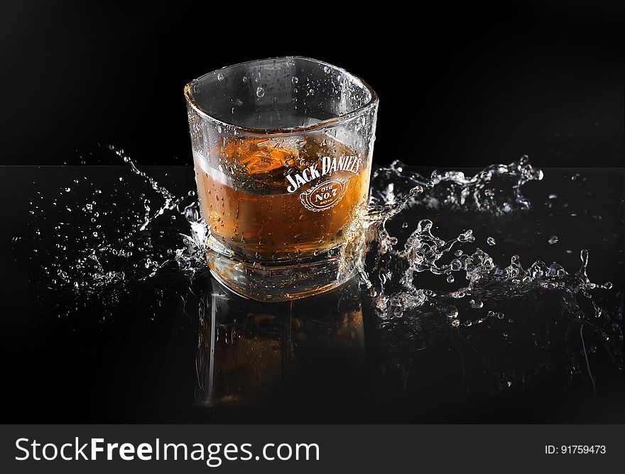 A glass of whisky splashing on black background.