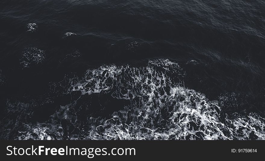 Background created by cold dark sea in the early morning with beginnings of white foam or froth spreading out. Background created by cold dark sea in the early morning with beginnings of white foam or froth spreading out.