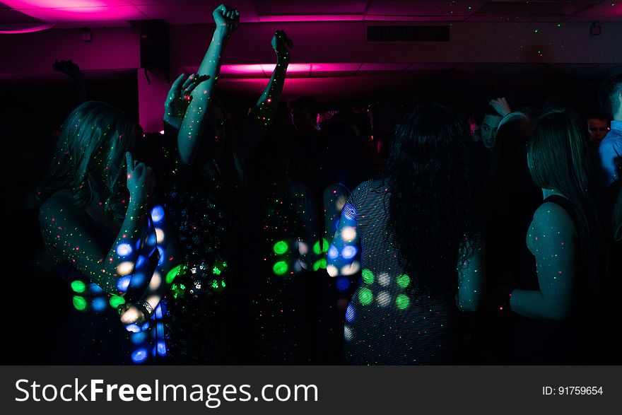 A group of people dancing in the nightclub with colorful lights. A group of people dancing in the nightclub with colorful lights.