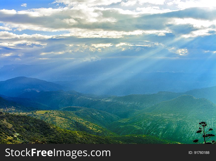 A view over a landscape with rays of lights coming down from the clouds. A view over a landscape with rays of lights coming down from the clouds.