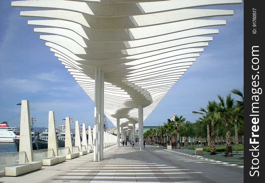 Ultramodern architecture to shield tourists from the sun when embarking from luxury cruise ships stopping in tropical resorts. Palm trees are growing alongside the sheltered walkway. Ultramodern architecture to shield tourists from the sun when embarking from luxury cruise ships stopping in tropical resorts. Palm trees are growing alongside the sheltered walkway.