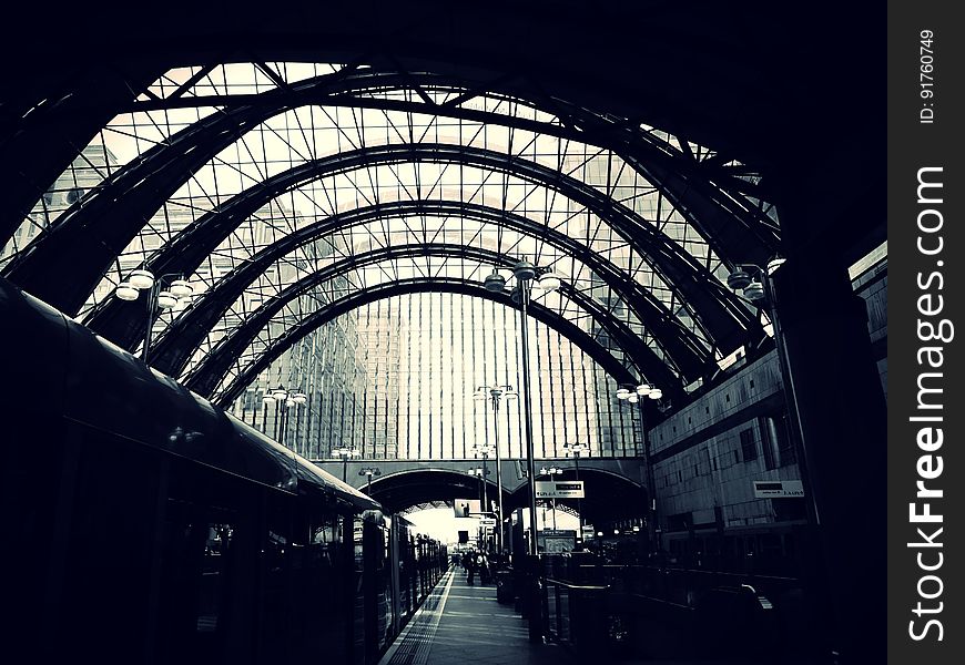 A view inside of a train station with arched glass ceiling.