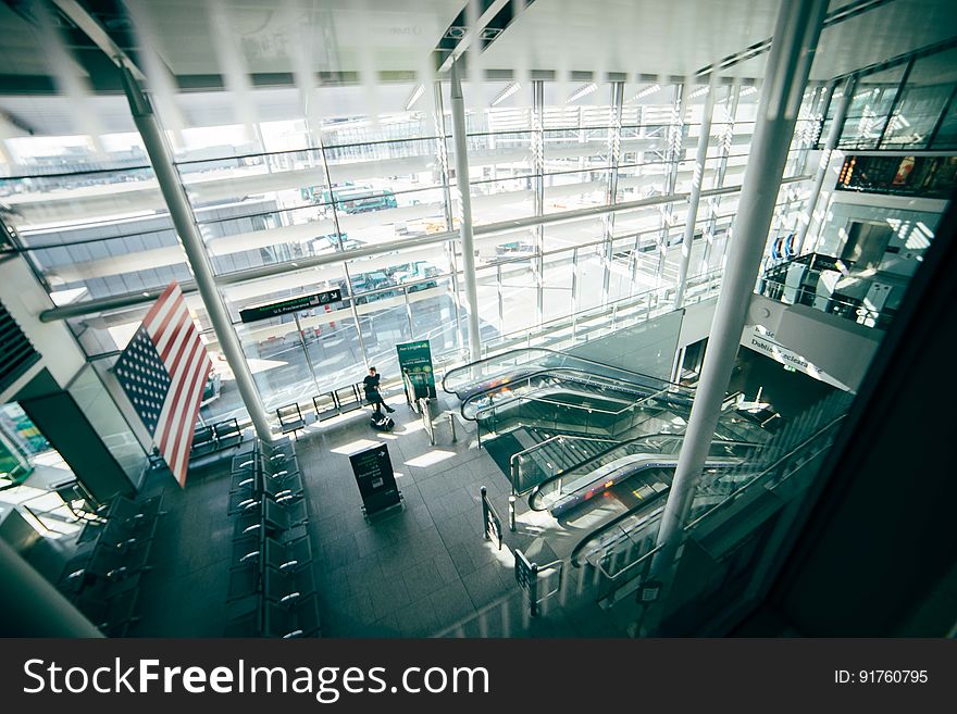 A view inside a commercial building or transit station with stairs and escalators and the American flag. A view inside a commercial building or transit station with stairs and escalators and the American flag.