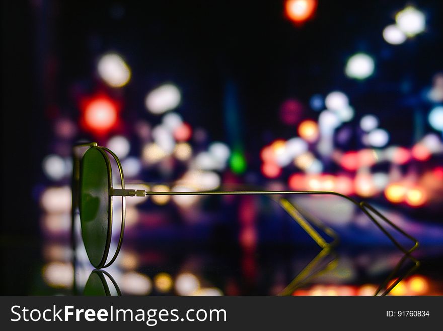 A pair of sunglasses on surface with bokeh lights on the background. A pair of sunglasses on surface with bokeh lights on the background.