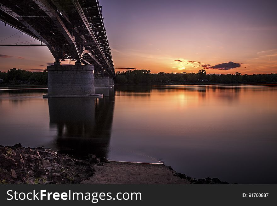 A bridge crossing a river with the sun setting in the background. A bridge crossing a river with the sun setting in the background.