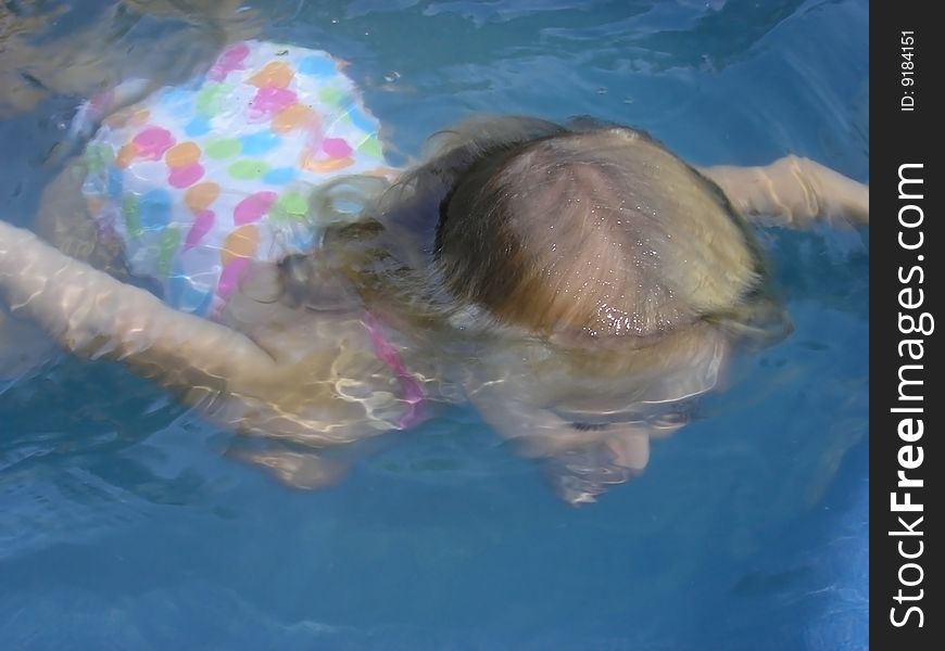 A young girl mostly under the water in a swimming pool or hot tub. 3 years old There is no raw file for this photo. A young girl mostly under the water in a swimming pool or hot tub. 3 years old There is no raw file for this photo.