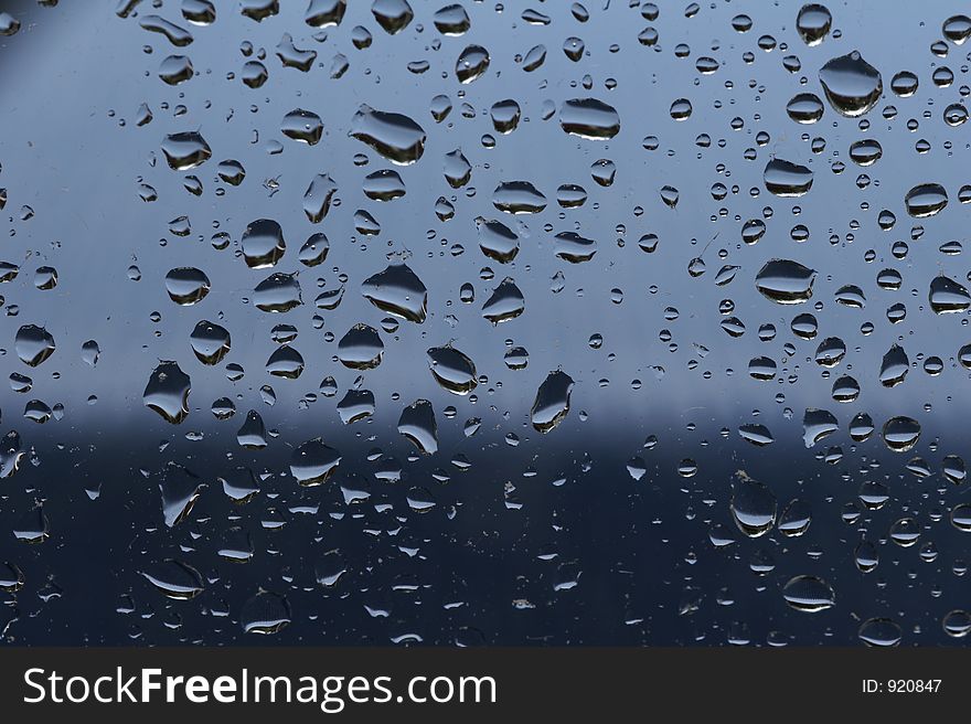 Raindrops at a window - blue background. Raindrops at a window - blue background